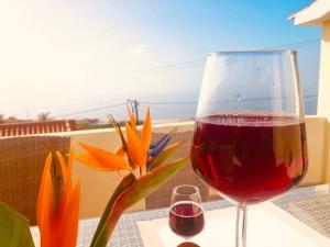a glass of wine sitting on a table with a flower at Casa Vista Mar -2 bedrooms,fantastic Seaview in Estreito da Calheta