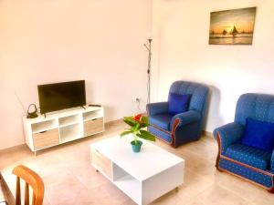 a living room with two blue chairs and a tv at Casa Vista Mar -2 bedrooms,fantastic Seaview in Estreito da Calheta