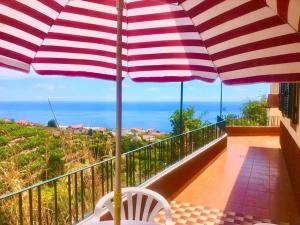 a balcony with an umbrella and a table and chair at Casa Vista Mar -2 bedrooms,fantastic Seaview in Estreito da Calheta