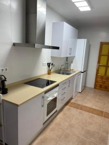 cocina con armarios blancos, fregadero y nevera en Apartamento CP en Cabo de Palos