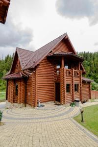 une grande cabane en bois avec un toit en gambrel dans l'établissement Смарагдовий пагорб, à Plavie
