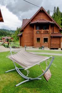 a hammock in front of a log cabin at Смарагдовий пагорб in Plav'ya