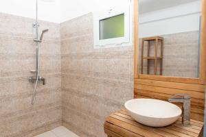 a bathroom with a sink and a shower with a television at B&Baobab in Bouéni