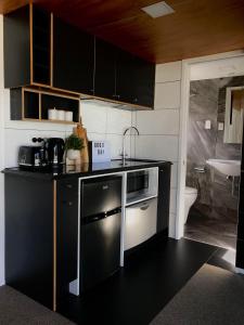 a kitchen with black cabinets and a sink and a stove at Onehunga Garden Tinyhouse in Auckland
