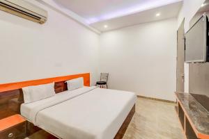 1 dormitorio blanco con 1 cama y TV en OYO Flagship 79953 Rose Inn Near Samaypur Badli Metro Station, en Nueva Delhi