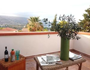a table with a green vase on a balcony at LE SORELLE Sea front -villa whit private pool in Scopello