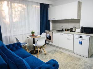 a living room with a blue couch and a kitchen at Escape Aparthotel in Suceava