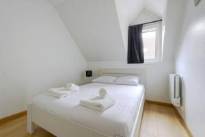 Un dormitorio con una cama blanca con toallas. en L'Elias : appartement de standing pour 6, en Rouen