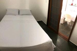 uma cama branca num quarto com uma janela em Cantinho do Sossego em Caraguatatuba