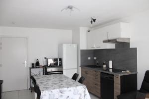 a kitchen with a table and a kitchen with a refrigerator at Appartement confortable avec parking privé in Schiltigheim