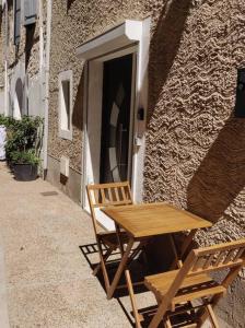 a wooden table and two chairs next to a building at Studio Indépendant dans Maison de Village in Alignan-du-Vent
