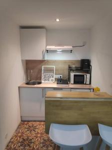 a kitchen with a counter with a microwave and a stove at Studio Indépendant dans Maison de Village in Alignan-du-Vent