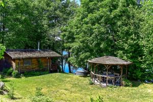 a cabin with a table and a gazebo in a yard at A private, cozy cottage on the shore of the lake, beautiful view in Aukštadvaris +69 photos