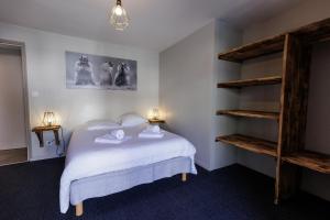 a bedroom with a bed with white sheets and shelves at la casse deserte in Arvieux