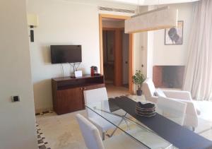 een woonkamer met een glazen tafel en witte stoelen bij Appartement Vizir 112 in Marrakesh