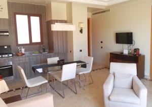 een woonkamer met een eettafel en witte stoelen bij Appartement Vizir 112 in Marrakesh