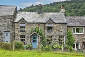una vieja casa de piedra con una puerta azul en Finest Retreats - Bryn Mair, en Dolwyddelan