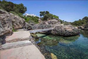 a bridge over a body of water with rocks at Vida Soladana - Cala en Forcat - piscina, playa, A/C, Smart TV... in Cala en Forcat