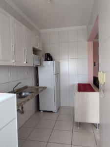 a kitchen with a white refrigerator and a sink at Apto150 m praia piscina Wi-Fi 6pessoas in Praia Grande