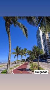 une rue avec des palmiers en face d'un bâtiment dans l'établissement Apto150 m praia piscina Wi-Fi 6pessoas, à Praia Grande