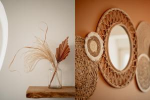 ein Spiegel an einer Wand neben einer Vase mit einer Pflanze in der Unterkunft Duplex cosy Le Boho in Guebwiller