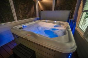 eine Badewanne mit blauem Wasser in einem Zimmer in der Unterkunft Par-Tee Haus I- Game Room & Hot Tub-Walk to Helen in Helen