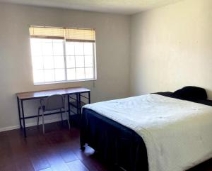 1 dormitorio con cama, escritorio y ventana en WHOLE Family - WholeVille en Sacramento