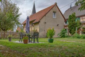 ein Haus mit einem Tisch und Stühlen im Hof in der Unterkunft Gîte indépendant - Bretzel et Bergamote in Richtolsheim