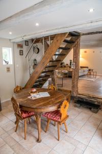 ein Esszimmer mit einem Holztisch und einer Treppe in der Unterkunft Gîte indépendant - Bretzel et Bergamote in Richtolsheim
