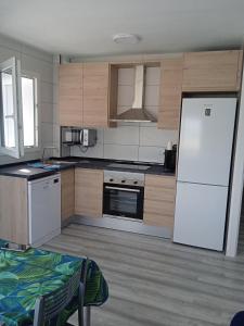 a kitchen with a white refrigerator and wooden cabinets at Vora Port in L'Ampolla