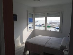 a bedroom with two windows with a view of a harbor at Vora Port in L'Ampolla
