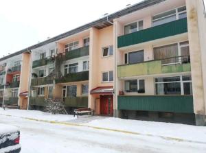 an apartment building in the snow with a bench in front at Baby friendly 1-bedroom rental w/ free parking in Sigulda
