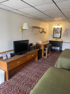 um quarto de hotel com uma televisão de ecrã plano e uma secretária em Knights Inn Mackinaw City em Mackinaw City