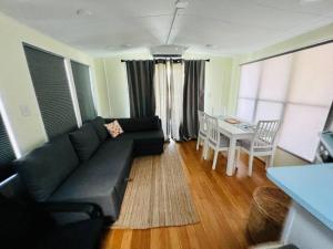 een woonkamer met een zwarte bank en een tafel bij Sunshine Tiny Home Pinecraft in Sarasota
