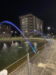 a fountain in the middle of a pond at night at Dream Apartment in Lukavica