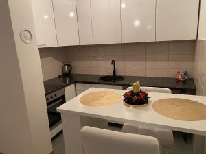 a kitchen with white cabinets and a table with a candle at Dream Apartment in Lukavica
