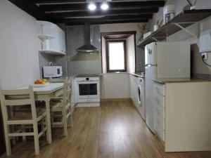 una cucina con elettrodomestici bianchi, tavolo e sedie di Casa rural La Bárcena Saja 