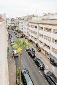 une rue de la ville avec des voitures garées et un palmier dans l'établissement Appartement Arribat Center Mall-Grande Terasse, à Rabat