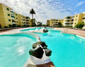 uma grande piscina com água azul num resort em Las Olas Sand em Playa del Inglés