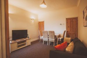 Una sala de estar con un televisor y una mesa con sillas. en COSY 5bed 2bath Well Equipped House in Coventry City near Amenties makes great DIGS, WI-FI, ON STREET PARKING, SMART TVS IN ROOMS, COOP SHOP 2MINS WALK, en Coventry