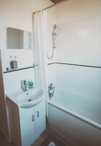 Un baño blanco con lavabo y ducha. en COSY 5bed 2bath Well Equipped House in Coventry City near Amenties makes great DIGS, WI-FI, ON STREET PARKING, SMART TVS IN ROOMS, COOP SHOP 2MINS WALK, en Coventry 13 fotos más