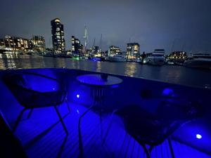 a bar with three chairs and a table at night at YACHT "X" - 44 FOOT MODERN YACHT ON 5 STAR OCEAN VILLAGE MARINA - minutes away from city centre and cruise terminals, Free parking ,SPA package available! in Southampton