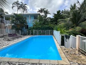 a blue swimming pool in front of a house at La Kaz à MaLou appartement de standing avec piscine et plage à 800m in Les Trois-Îlets