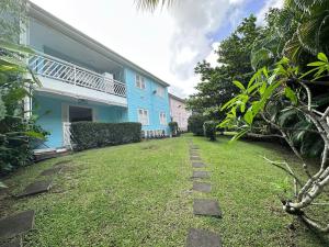 a yard of a blue house with a walkway at La Kaz à MaLou appartement de standing avec piscine et plage à 800m in Les Trois-Îlets