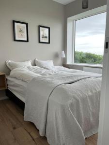 a white bedroom with a bed and a window at Beautiful house with an outstanding view in Hvolsvöllur
