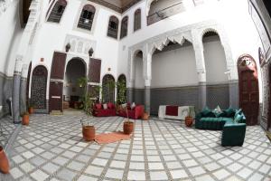um átrio com sofás e vasos de plantas num edifício em hostel Dar belghiti em Fez