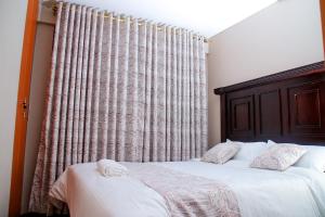 內羅畢的住宿－Elly Residence，一间卧室配有床和带窗帘的窗户