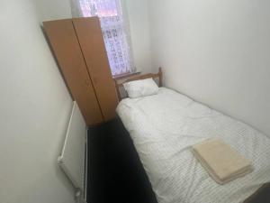 a small bedroom with a bed and a cabinet at London Recently Refurbished House in Thornton Heath