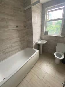 a bathroom with a tub and a toilet and a sink at London Recently Refurbished House in Thornton Heath