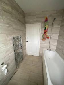 a bathroom with a tub and a white door at London Recently Refurbished House in Thornton Heath